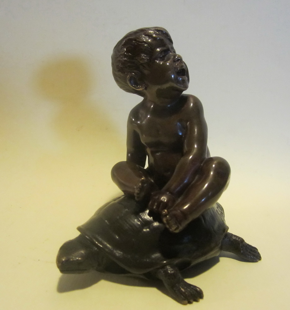 antique bronze: a baby boy riding on the back of a turtle,